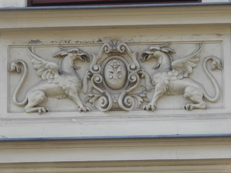 Two griffins flanking heraldic shield with fleur-de-lis on building facade