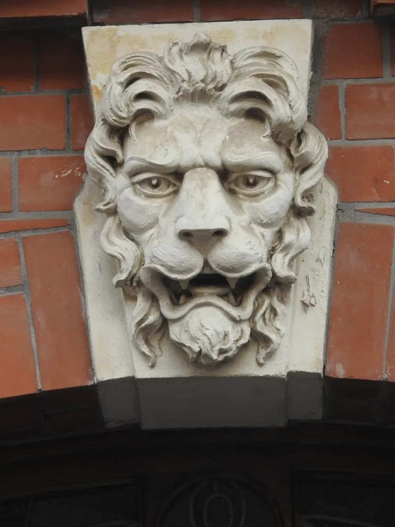Stone lion mascaron keystone on brick building facade